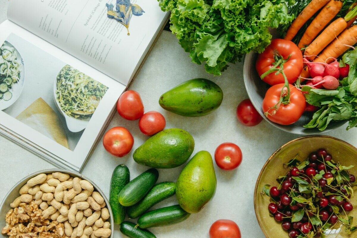An appetizing display of fresh fruits and vegetables with a cookbook, perfect for healthy recipes.